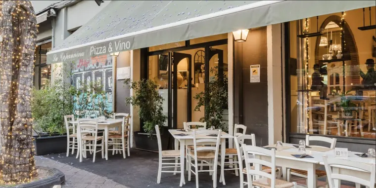 I tavoli bianchi all'esterno del locale, lungo la via, sotto le tende